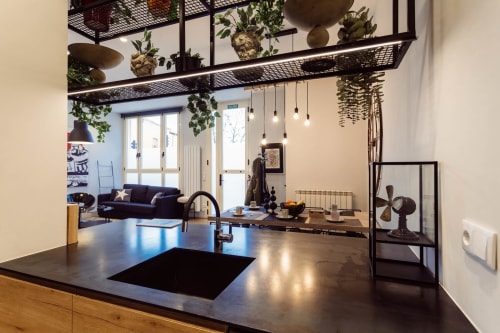 Cocina de loft moderno en Burgos con encimera negra, electrodomésticos de acero inoxidable, plantas colgantes y sala abierta