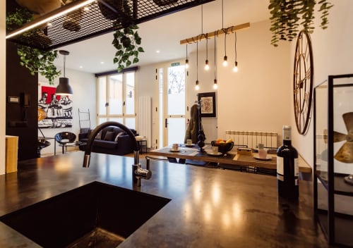 Moderno loft en Burgos con cocina abierta, comedor, salón, decoración industrial, iluminación colgante y vista de ciudad