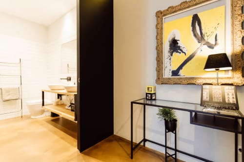 Entrada de loft moderno en Burgos con arte contemporáneo, consola negra y baño abierto