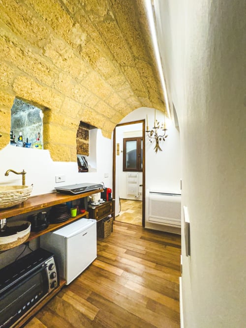 Cucina moderna con soffitto in pietra a volta, banconi in legno e elettrodomestici bianchi nell'appartamento CorteLirice Paradiso