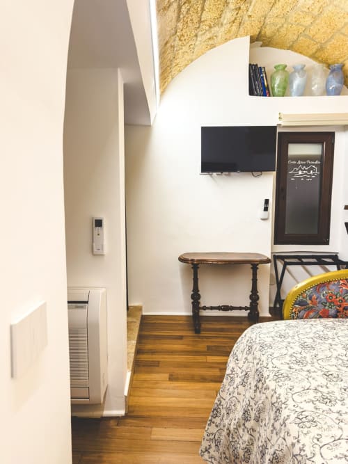 Camera da letto Paradiso di CorteLirice con pavimenti in legno, biancheria con motivi, TV a muro e arredi classici