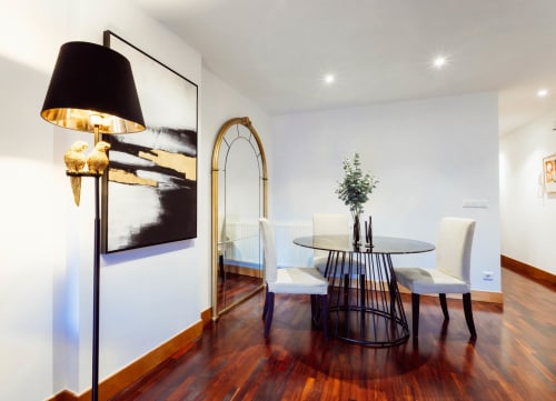 Comedor moderno en apartamento Five Senses, Burgos con mesa redonda, sillas color crema, pisos de madera y arte contemporáneo