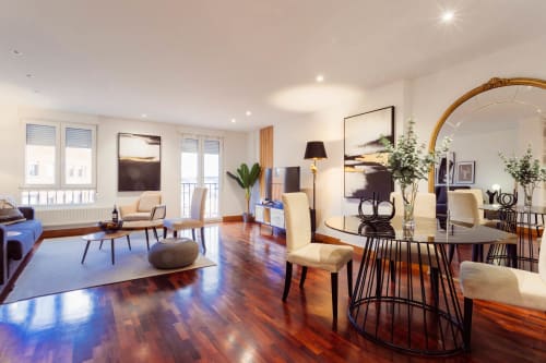 Salón moderno en apartamento de Burgos con suelos de madera, mesa de comedor, sillas color crema y vistas a la ciudad desde el balcón