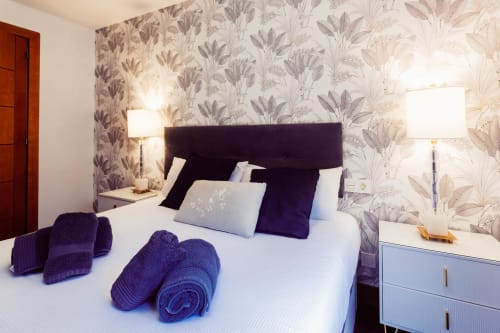Habitación moderna en Five Senses by Unique Rooms en Burgos con acentos púrpura, papel tapiz floral y vistas a la ciudad