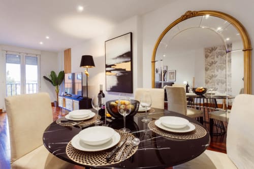 Elegante comedor en apartamento Five Senses, Burgos con mesa de mármol negro redonda, montaje blanco y amplio