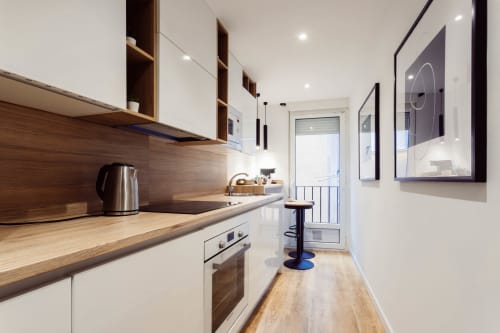 Cocina moderna del apartamento Five Senses en Burgos, con encimeras de madera, muebles blancos y zona de comedor