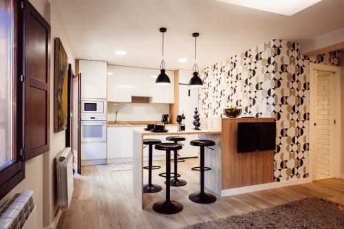 Cocina y salón diáfanos modernos en apartamento Arco San Esteban, Burgos con papel pintado geométrico y lámpara colgante negra