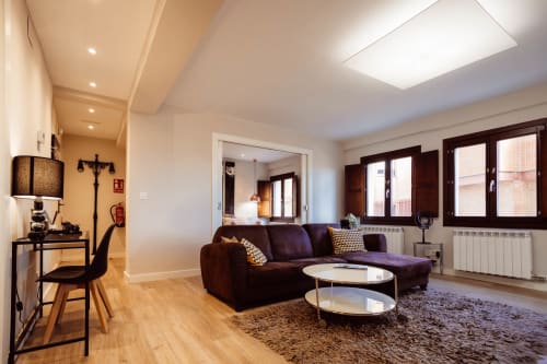 Sala moderna del apartamento Arco San Esteban en Burgos con sofá púrpura, suelo de madera y vistas a las montañas