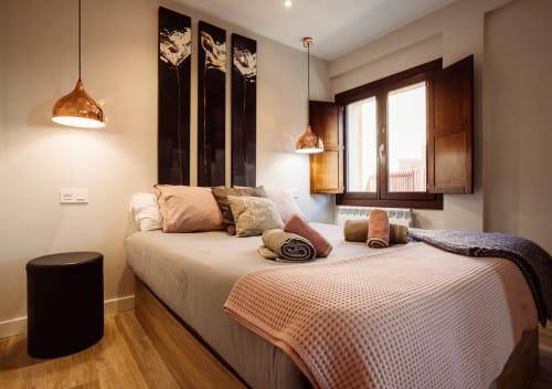 Habitación moderna en Arco San Esteban, Burgos con cama queen, lámparas colgantes de cobre, detalles de madera oscura y vistas a las montañas
