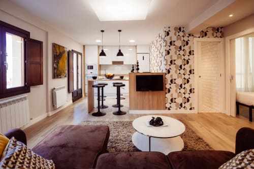 Moderno salón con cocina, muebles de madera, azulejos geométricos y vistas a la montaña en Burgos