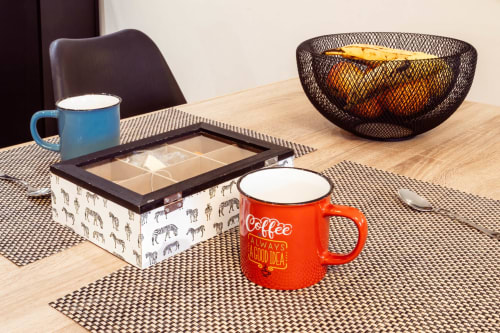 Acogedora mesa de apartamento con tazas azules y rojas, caja de té y frutero metálico en Unique Rooms, Burgos