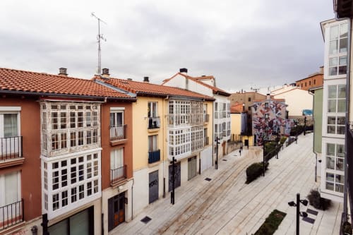 Edificios históricos coloridos bordeando una plaza peatonal en Burgos, España, mostrando arquitectura tradicional con vistas de la ciudad