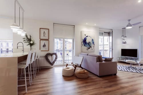 Moderno apartamento diáfano en Burgos con sofá púrpura, isla de cocina, suelos de madera y vistas de la catedral desde el balcón