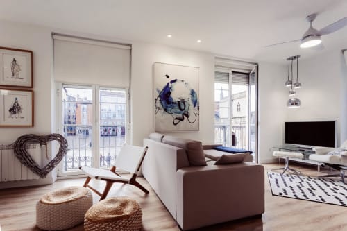 Moderno salón de apartamento en Burgos con sofá marrón, vistas al balcón, suelos de madera y vistas a la catedral