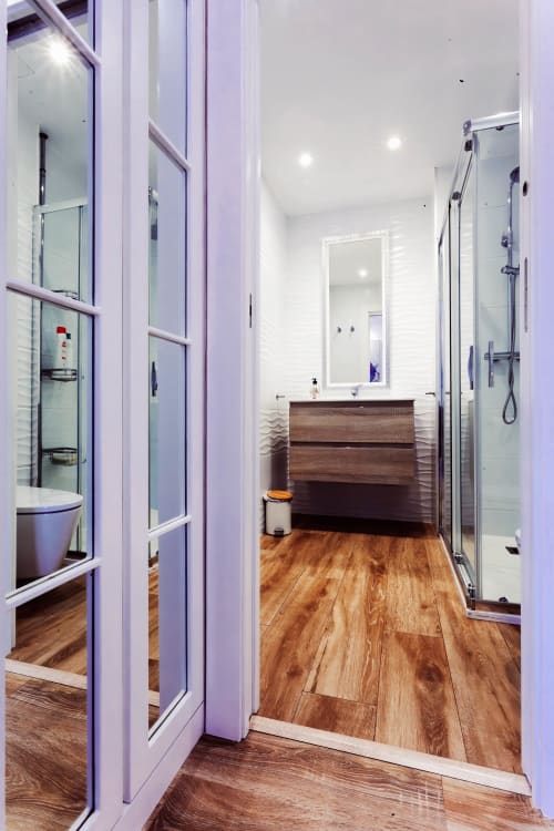 Baño moderno en apartamento Five Balconies, Burgos con piso de madera, tocador marrón, espejo y ducha de cristal