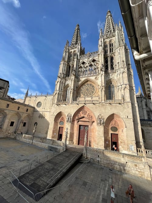 Fachada gótica de la Catedral de Burgos con sus gemelas agujas, vista desde el patio del apartamento Unique Rooms en un día despejado y soleado