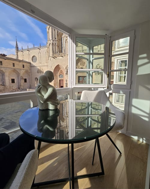Apartamento moderno en Burgos con vistas a la catedral, mesa de cristal, muebles contemporáneos y ventanas iluminadas con vista al Gótico