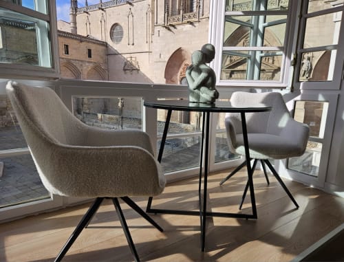 Moderna sala de estar en apartamento de Burgos con vista a la Catedral, dos sillones color crema, mesa redonda y arquitectura gótica