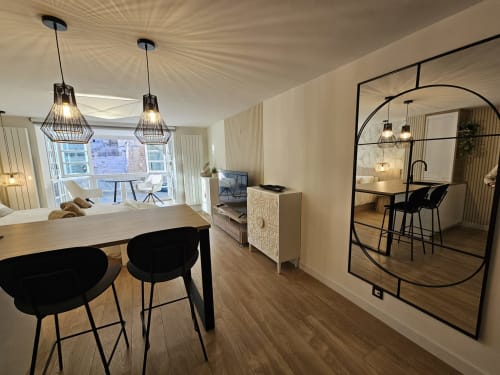 Apartamento moderno en Burgos con comedor, taburetes negros, lámparas colgantes y pared espejo que refleja la Catedral