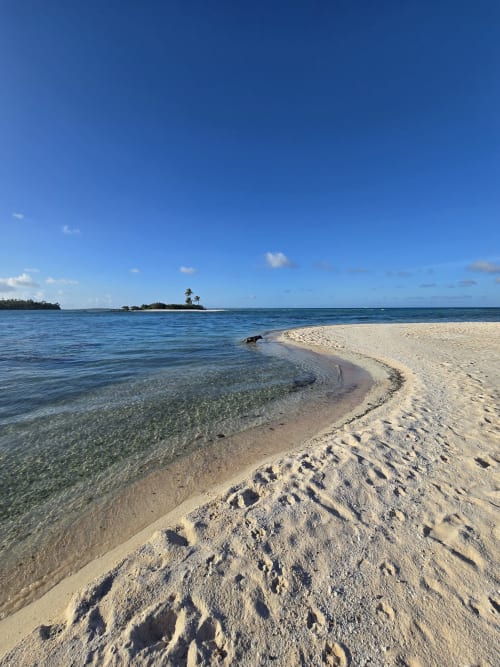 Pristine white sand beach with crystal clear turquoise water at Tikehau Herearii in French Polynesia, featuring footprints