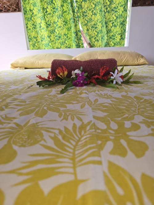 Bed at Tikehau Herearii with tropical flower garland and yellow patterned bedding in Tuherahera
