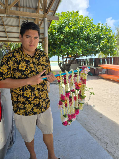 Staff member at Tikehau Herearii holding colorful flower garlands at beachside resort in Tuherahera, French Polynesia