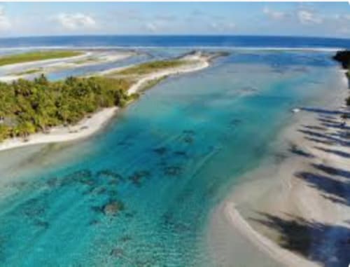 Aerial view of Tikehau atoll lagoon with turquoise waters, white sand beaches, and lush vegetation in French Polynesia