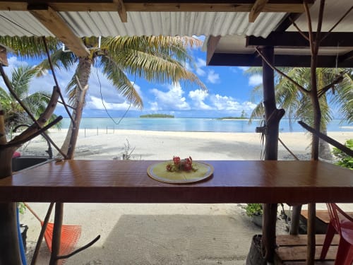 Tikehau Herearii cottage sea view with sandy beach, palm trees, and turquoise lagoon from dining table