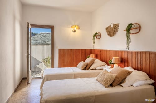 Chambre moderne de la villa La Conciergerie du Cap Corse avec lits jumeaux, terrasse vue mer et éléments décor muraux