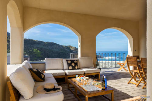 Terrasse de la Villa ANNONCIADE avec ouvertures voûtées, vue sur mer, mobilier en bois et paysage méditerranéen à Centuri, Corse