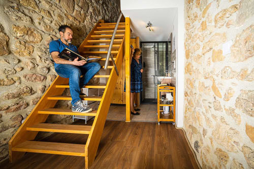 Man reading on wooden stairs in stone troglodyte room at Au Château De Villelongue, Villelongue-d'Aude
