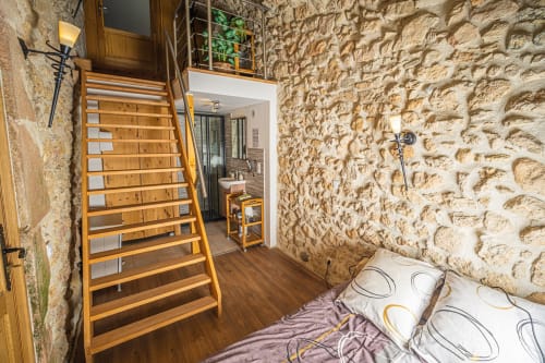 Troglodyte room at Au Château De Villelongue with wooden stairs, stone walls, and mountain views in Villelongue-d'Aude