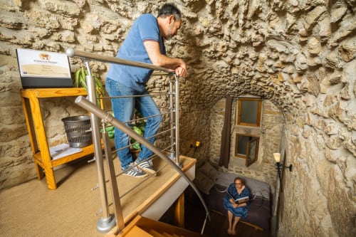 Man descending stairs in troglodyte cave room at Au Château De Villelongue, Villelongue-dʼAude