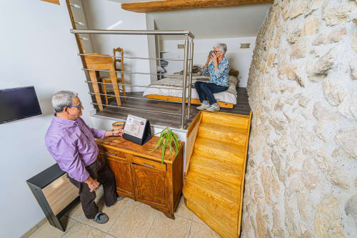 Couple dans la chambre principale de l'étable du Château de Villelongue, Villelongue-d'Aude, avec mobilier en bois et murs en pierre
