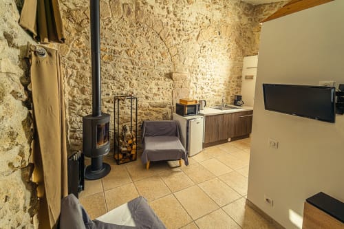 Chambre rustique en pierre au Château De Villelongue avec poêle à bois, TV, coin séjour et kitchenette à Villelongue-d'Aude