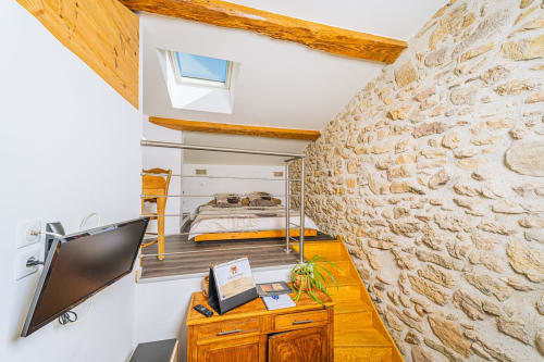Chambre principale l'étable au Château De Villelongue : pierres apparentes, poutres en bois, puits de lumière et équipements modernes