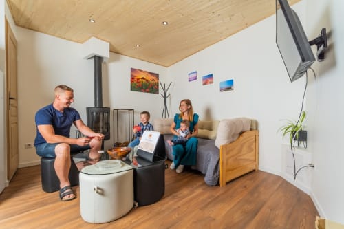 Famille se détendant dans le salon du cottage à l'école du Château de Villelongue avec TV et photos de montagne aux murs