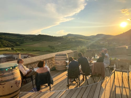 Les invités dégustent un dîner au coucher du soleil sur la terrasse du Château de Villelongue, avec vue sur les vignobles vallonnés de l'Aude, en France