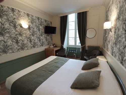 Comfortable double room at Le Pavillon Saint Martin Hotel in Souillac with patterned wallpaper, city view window, TV, and