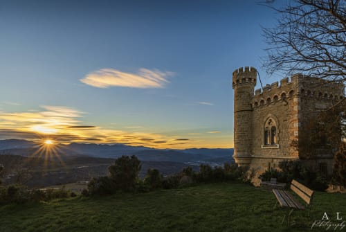 Torre de castillo de piedra al atardecer con vista a la valle de Villelongue-d'Aude con banco en primer plano
