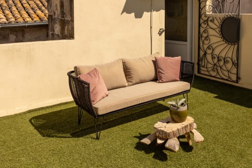 Outdoor courtyard seating at Le Prieuré Notre-Dame, Montfrin with cream sofa, pink cushions and wooden side table on