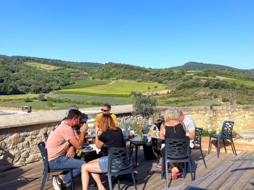 Convives dînant sur la terrasse du Château de Villelongue avec vue sur le vignoble et les collines ondulantes de l'Aude, France