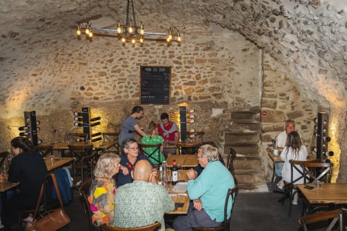 Guests dining in a rustic stone restaurant at Au Château De Villelongue, a French B&B in Villelongue-dʼAude, with warm
