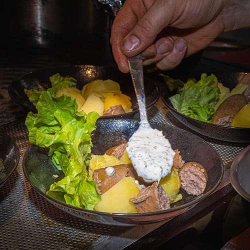 Un serveur versant une sauce aux herbes sur un plat de bœuf à Au Château De Villelongue, Villelongue-d'Aude