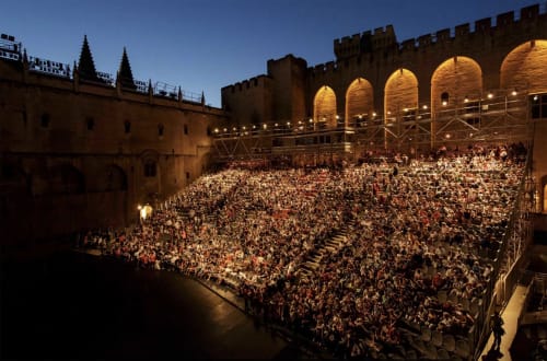 Medieval courtyard at Le Prieuré Notre-Dame in Montfrin hosts large evening gathering under arched lighting
