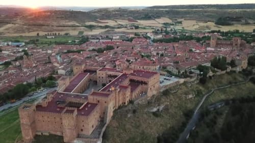 Castillo medieval que domina el pueblo de Arbancon con tejados rojos al atardecer en la España rural