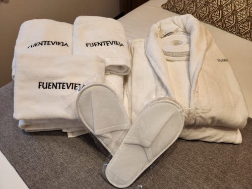 Lujosas toallas y pantuflas blancas con la marca Fuente Vieja en la posada rural de Arbancón