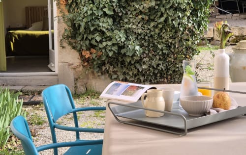 Zithoek op het terras van Moulin Renaudiots in Autun met blauwe stoel, wit aardewerk en met klimop begroeide muren