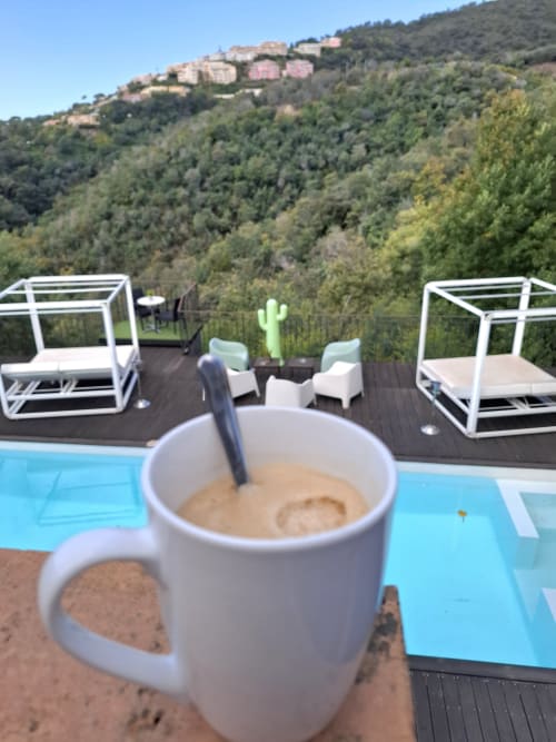 Tasse de café à la piscine de Villa Colina avec vue sur les collines boisées et les villas de Mandelieu-la-Napoule