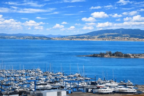Marina de Baiona con veleros frente a las aguas azules del Mediterráneo y montañas costeras